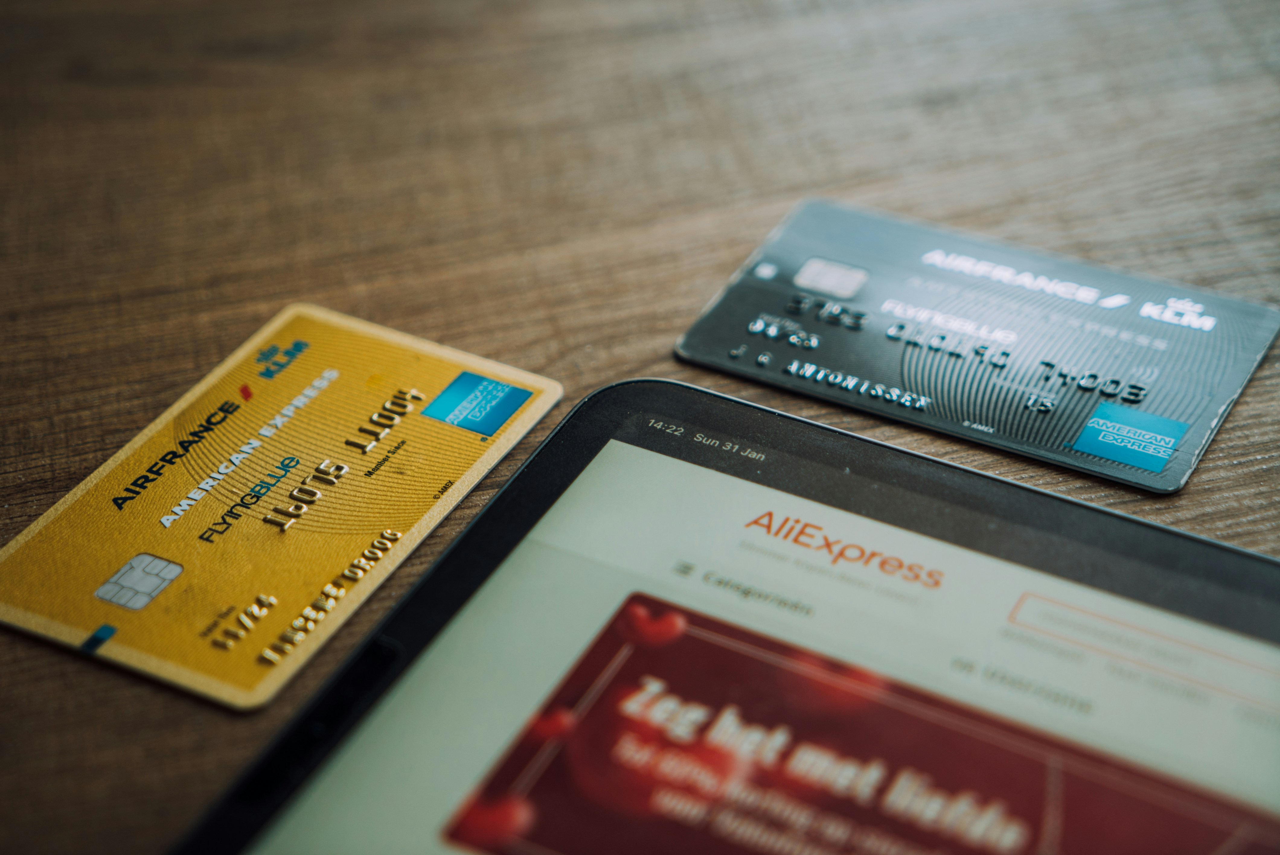 알리익스프레스 페이지가 켜져 있는 화면 옆으로 신용카드 두개가 바닥에 놓여있다.