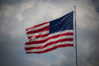 구름이 잔뜩낀 하늘에 대형 '미국' 국기가 펄럭이고 있다.