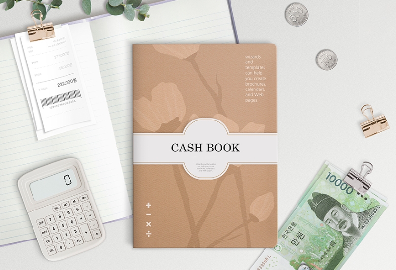 CASH BOOK이라고 적힌 노트가 놓여져 있으며, 우측에는 동전과 만원짜리 지폐가, 좌측에는 계산기와 영수증이 놓여져있다.