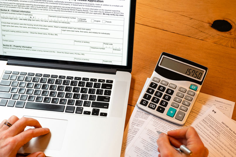 테이블 위에 노트북, 계산기와 각종 서류를 가지고 '세금' 계산을 하고 있는 모습이다.