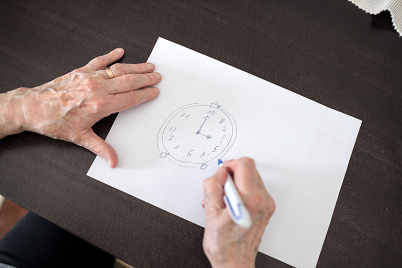 한 '노인'이 흰 종이 위에 '시계'를 그려넣고 있는 모습이다.