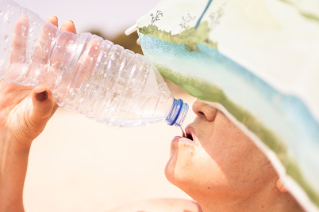 한 사람이 햇볕아래에서 생수통에 담긴 '물'을 마시고 있는 모습이다.