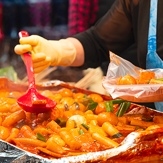 전통시장의 떡볶이. 가판대의 떡볶이를 접시에 담고 있다.