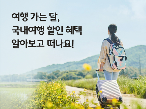 노란 꽃이 피어있는 길로 캐리어를 끌고 걸어가는 여성의 뒷 모습